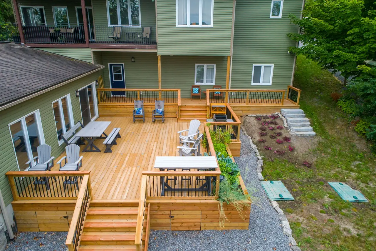 A backyard deck with chairs and a table beside a house