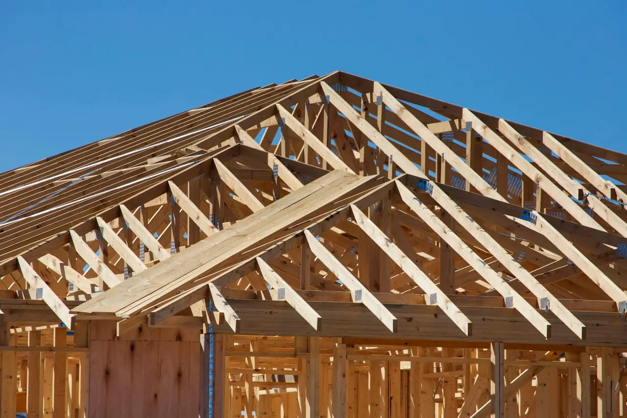The wood framing of a new house against a blue sky