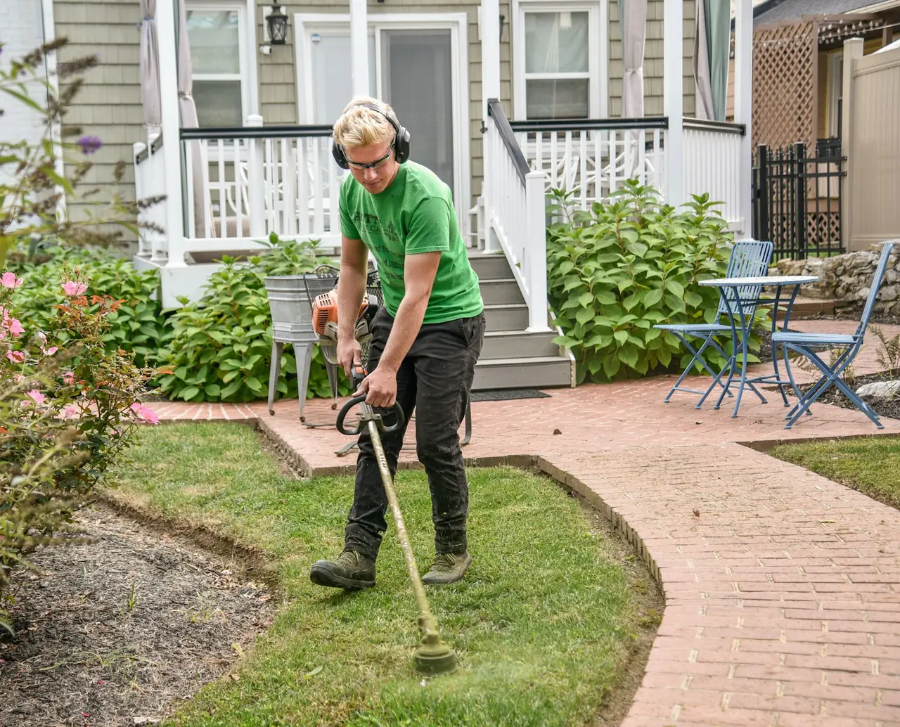 A landscaper trimming the edge of a front lawn