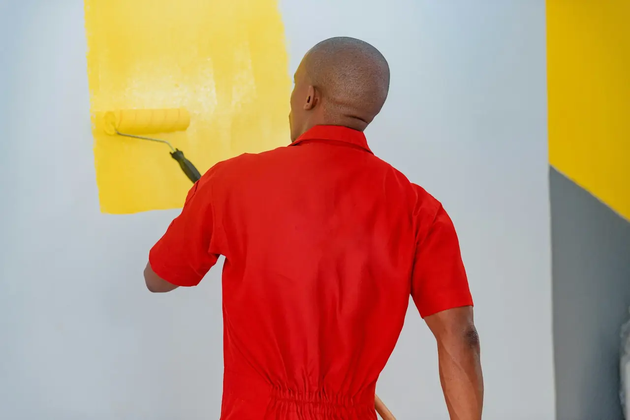 A painter rolling yellow paint onto a wall