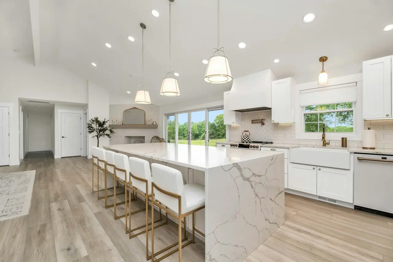 A bright kitchen with white cabinets and a marble island